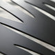 The close-up of Oscura Dynamic Flow Black Abstract Metal Wall Art by Giant Sculptures showcases a sleek metallic surface with elongated cutouts, highlighting modern sophistication. The lighting enhances its texture, while the blurred background accentuates its dynamic flow and unique design.