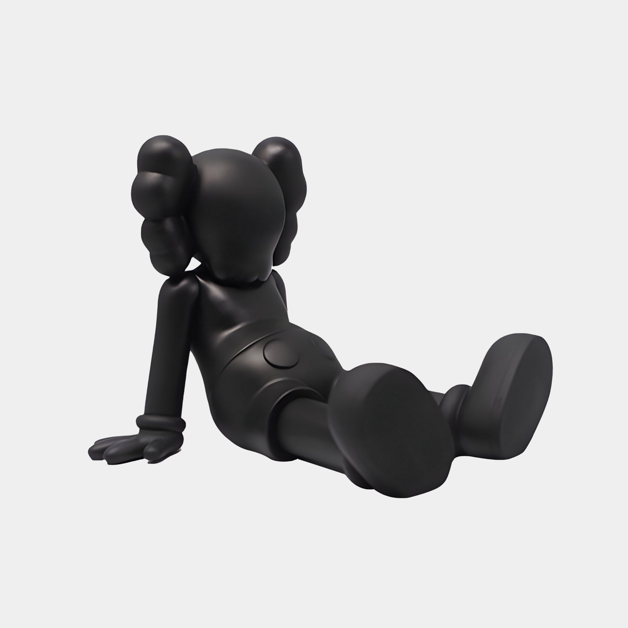 The Obsidian Black Iconify Daydream Sculpture by Giant Sculptures features a contemporary design, reclining with extended legs supported by hands. It showcases cartoonish elements like large gloves, shoes, and head shapes, epitomizing modern relaxation. Size: 85cm.