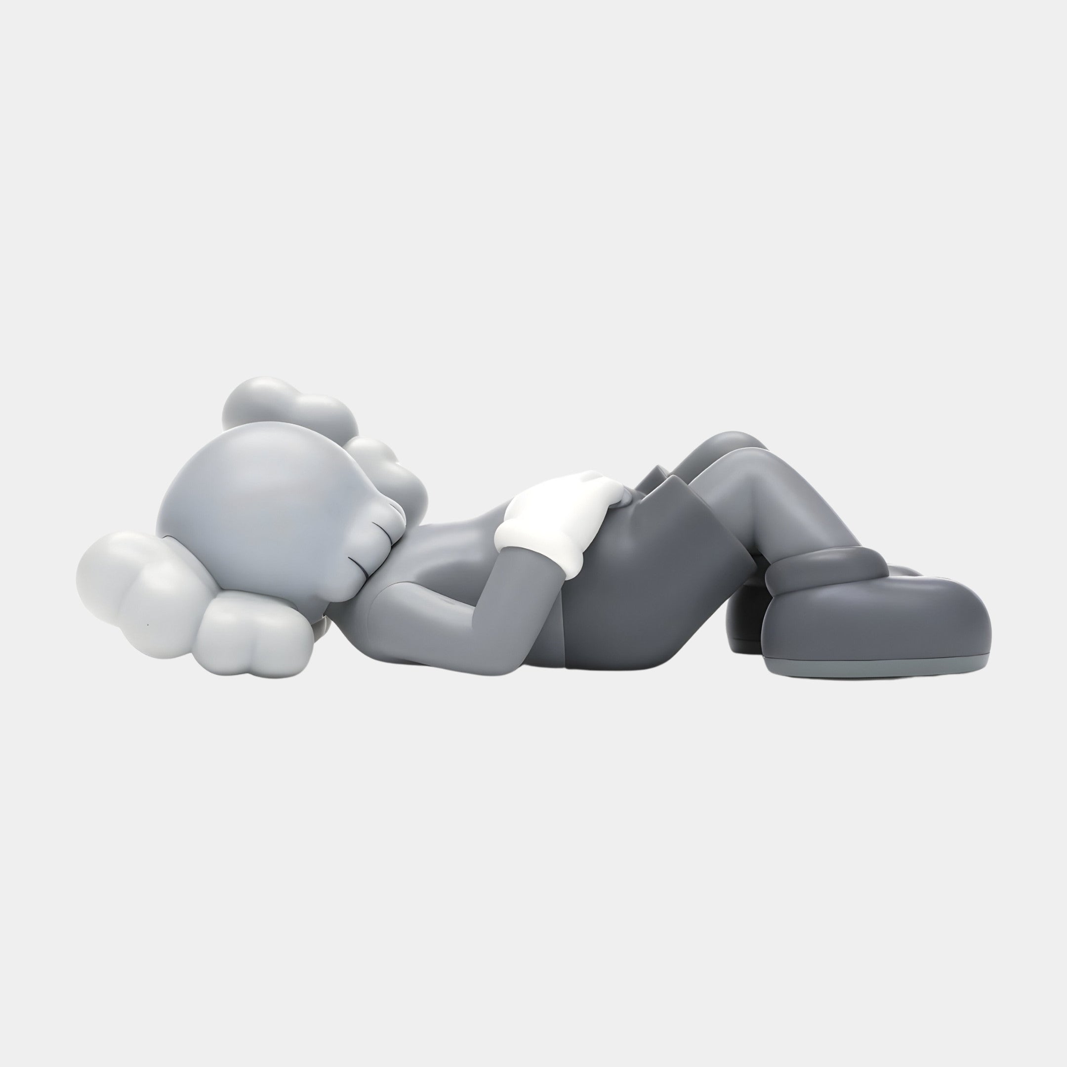 The Soft Grey Iconify Peace Sculpture by Giant Sculptures is a 110cm resin piece featuring a grayscale figure with a round head, puffy features, bent knees, and arms on its torso, wearing gloves and boots. Its ideal for modern interiors with neutral palettes against a light gray background.