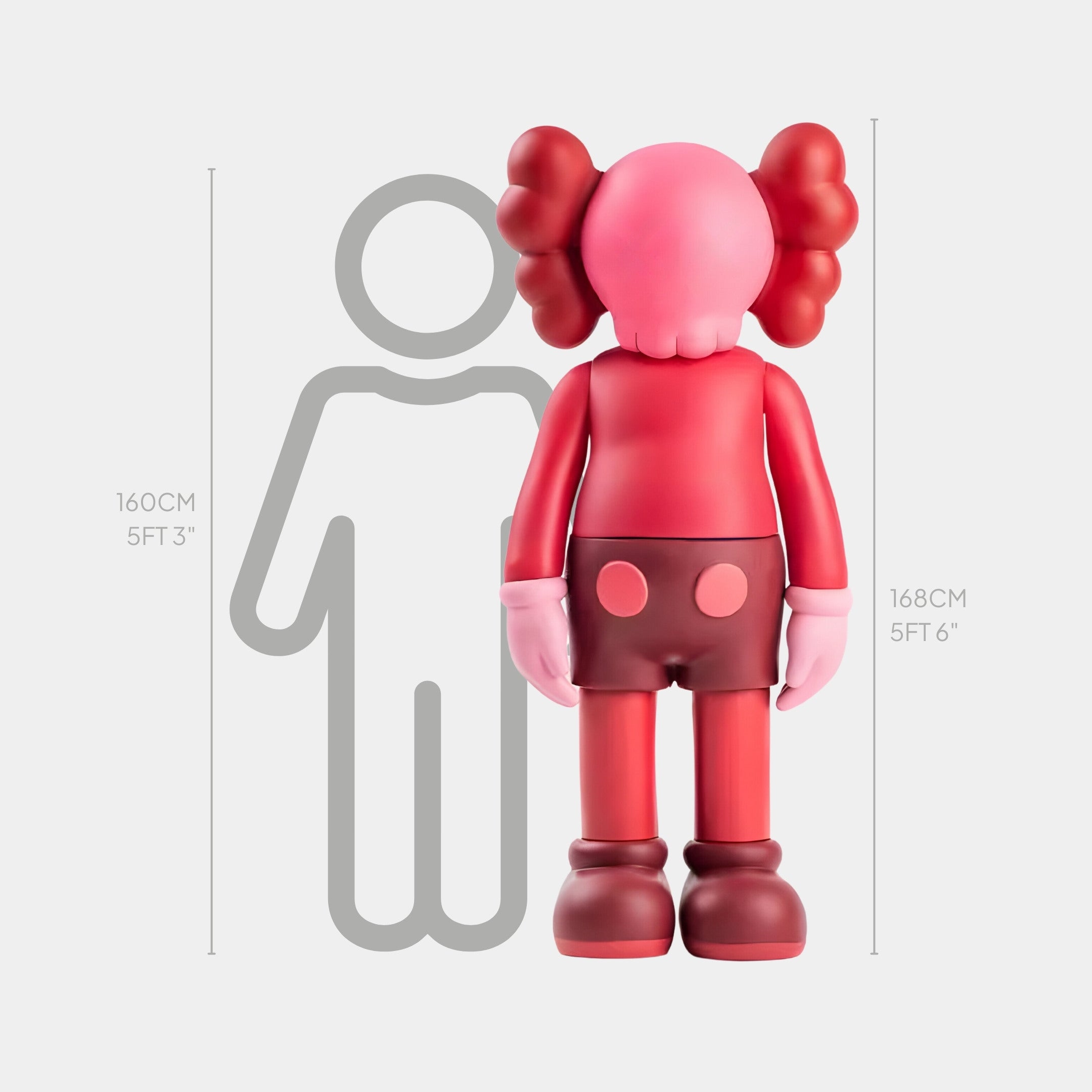 The Blush Ruby Iconify Standing Sculpture by Giant Sculptures is a 168 cm (56) tall, pink and red cartoon character figurine with X-shaped eyes and large ears, exuding contemporary artistry beside a 160 cm (53) gray human outline.