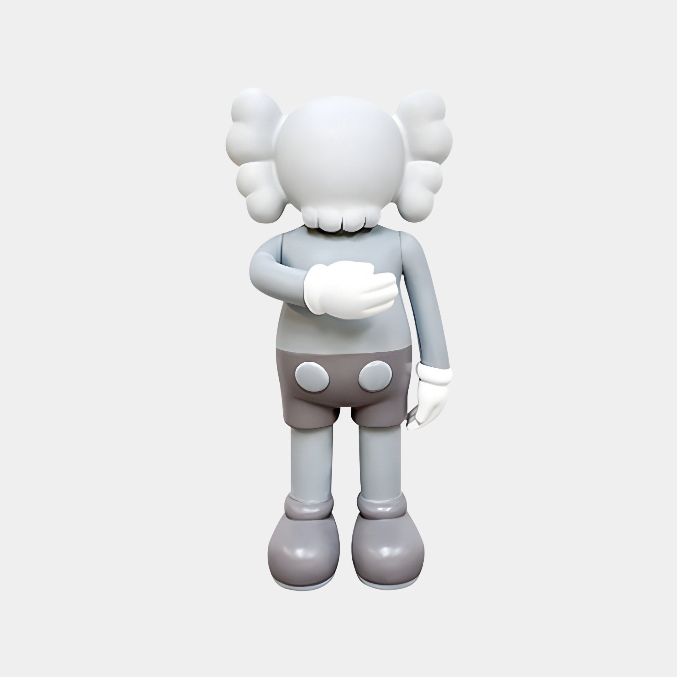 The Soft Grey Iconify I Dance Sculpture by Giant Sculptures captures a gray cartoon figure with X-shaped eyes, bone-like puffy ears, and large gloves and shoes, facing away. At 70cm tall, it adds whimsical contemporary elegance to luxury interiors with its shorts featuring two white buttons.