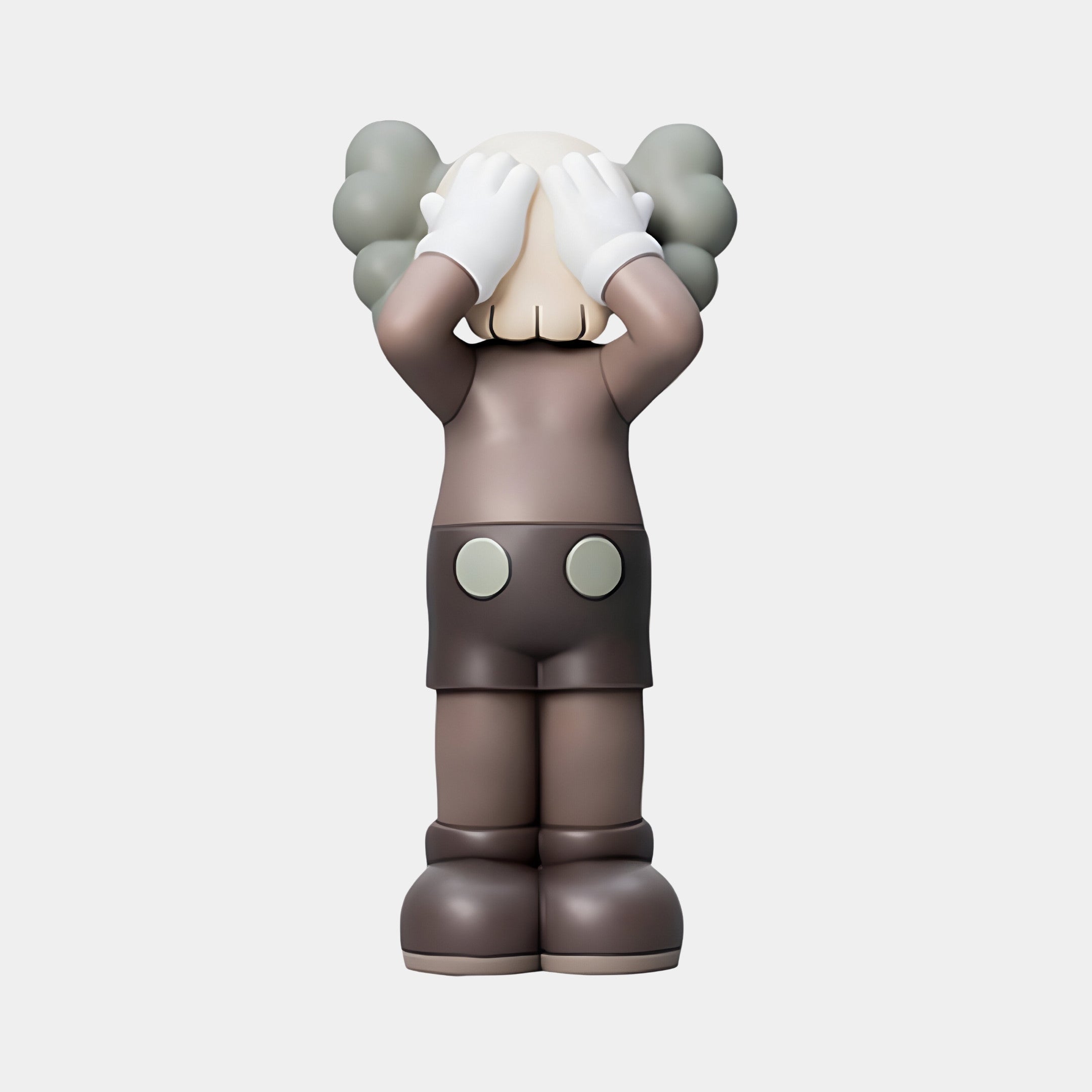 The Hazelnut Brown Iconify Silent Cry Sculpture by Giant Sculptures features a cartoon-style figure with gloved hands covering its eyes, a round body, large shoes, two buttons on its shorts, and cloud-like hair against a white background.