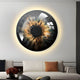 A modern living room features the Genesis Golden Halo, a Giant Sculptures piece, measuring H100cm x W100cm. This 3D crystal resin porcelain LED wall art resembles a close-up of an eye with an abstract fiery iris and dark pupil, softly backlit above a white sofa with orange and black pillows.