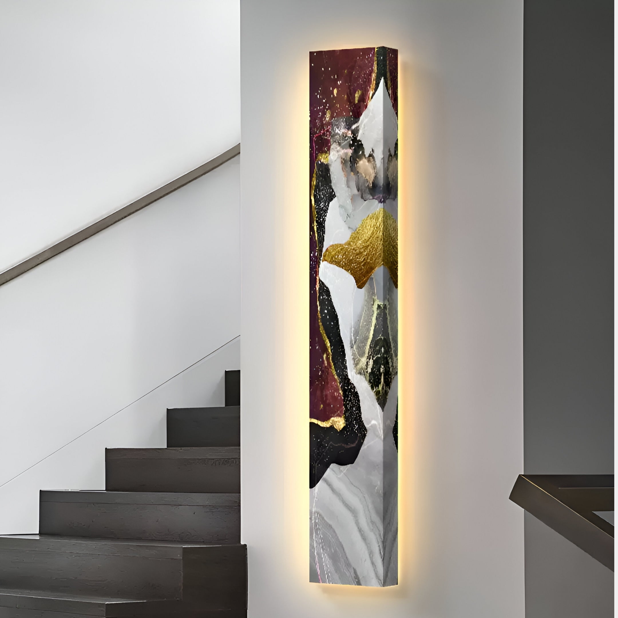 The Floren Crimson Burst Canvas LED Wall Art by Giant Sculptures showcases an abstract blend of black, white, gold, and maroon hues on a vertical canvas. It is mounted on a white wall with backlighting that creates a soft glow. Dark stairway steps are visible nearby.