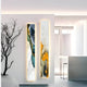 A modern room displays two tall pieces from Giant Sculptures Floren Amber Glow Canvas LED Wall Art collection, featuring blue, gold, and white hues on a backlit wall. A sleek white counter with ambient lighting and a bare-branched plant completes the gallery-worthy look.