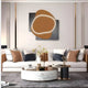 A modern living room showcases a white couch adorned with neutral-toned cushions. Above, the Gleam Russet Harmony 3D Leather LED Wall Art by Giant Sculptures adds a unique glow. A round coffee table with decor rests on a gray rug, while vertical wall slats enhance the chic ambiance.