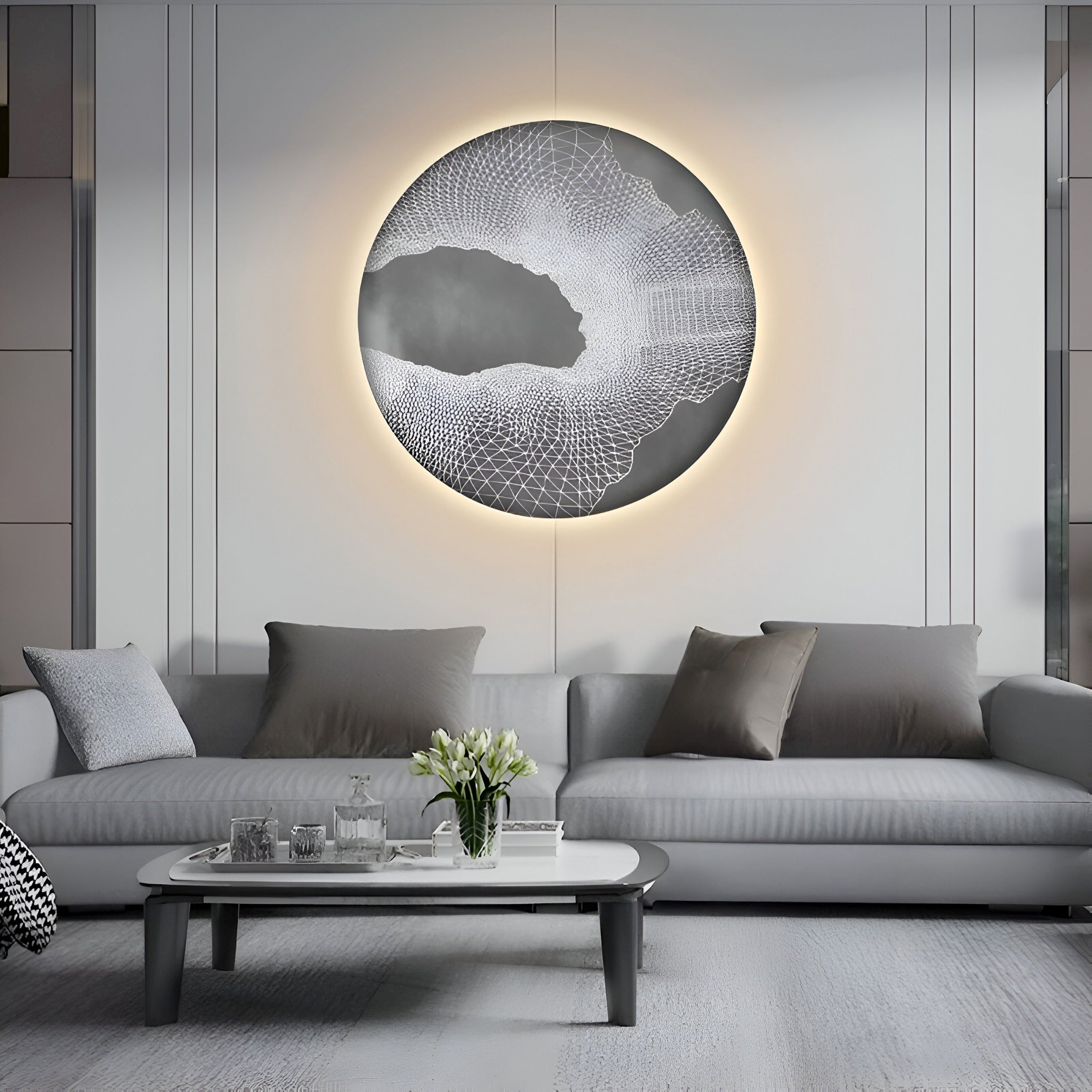 A modern living room showcases a gray sofa with assorted pillows, complemented by a glass coffee table with flowers. The centerpiece is the Earthlight Twilight Aura 3D Textured Oil Painting LED Wall Art by Giant Sculptures, enhancing the space with its illuminated design.