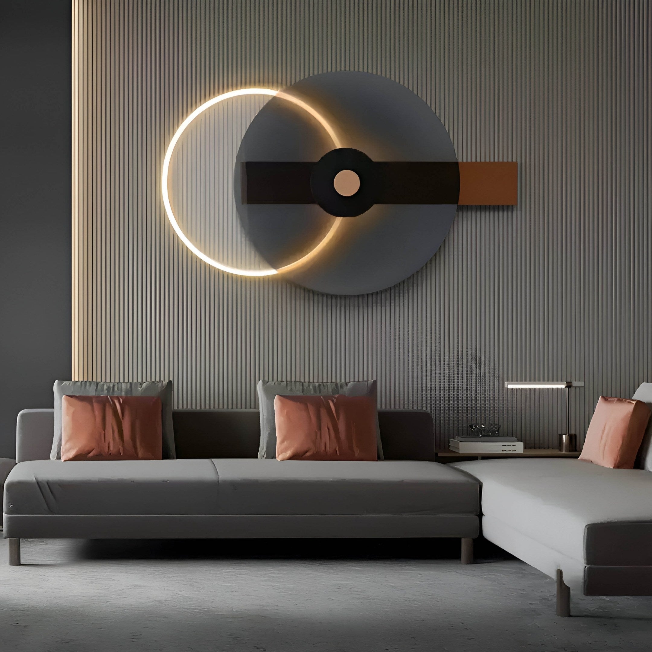 In a modern living room, charcoal bronze gray couches adorned with orange pillows are complemented by the Eclipse I Charcoal Bronze Acrylic 3D LED Wall Art by Giant Sculptures, illuminating the textured wall with layered geometric shapes. A small table and lamp complete the sophisticated minimalist decor.