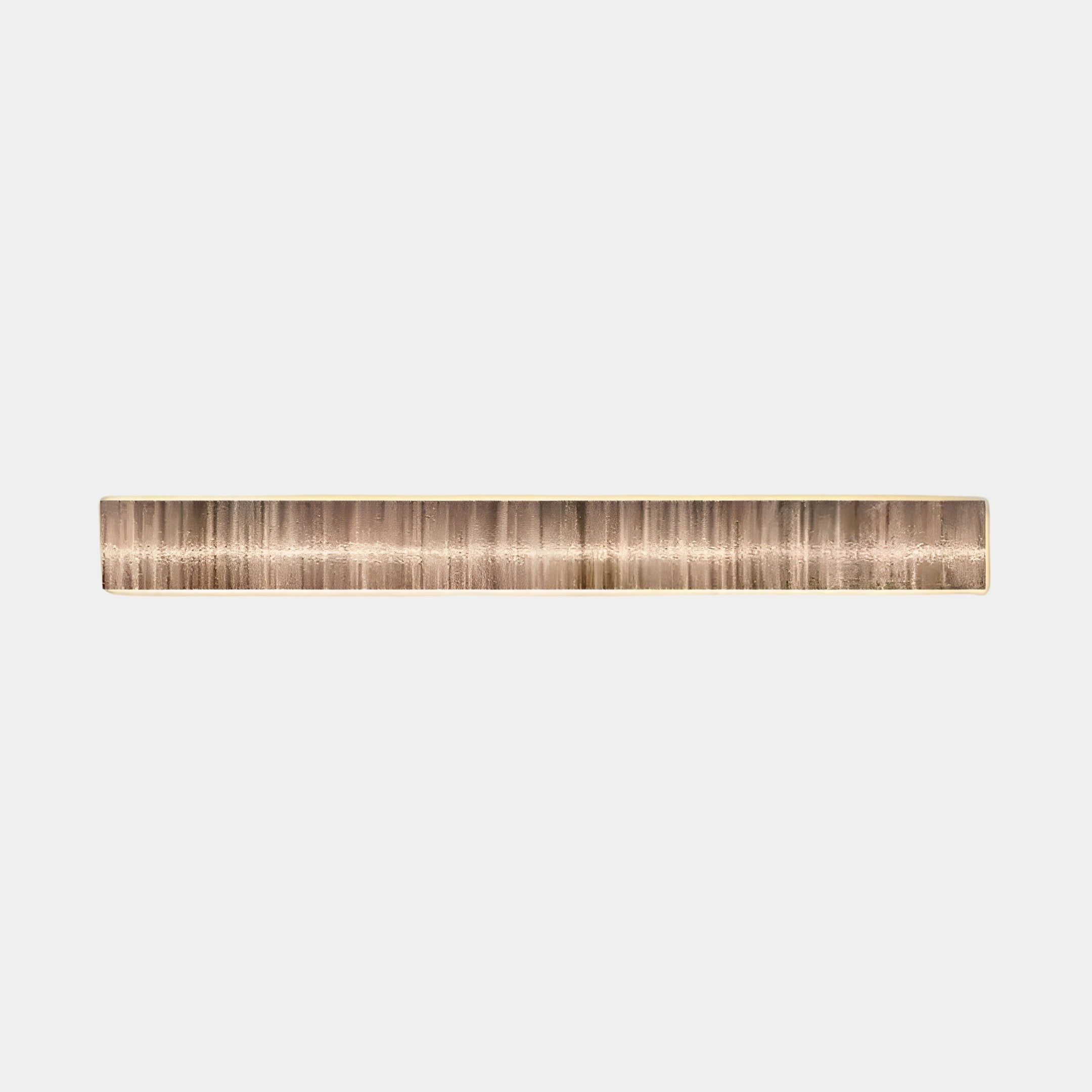 The Radiance Sandy Gold Canvas LED Wall Art by Giant Sculptures is a long, slender, cylindrical piece with a warm metallic finish featuring subtle vertical lines that evoke coastal warmth against a plain white background.