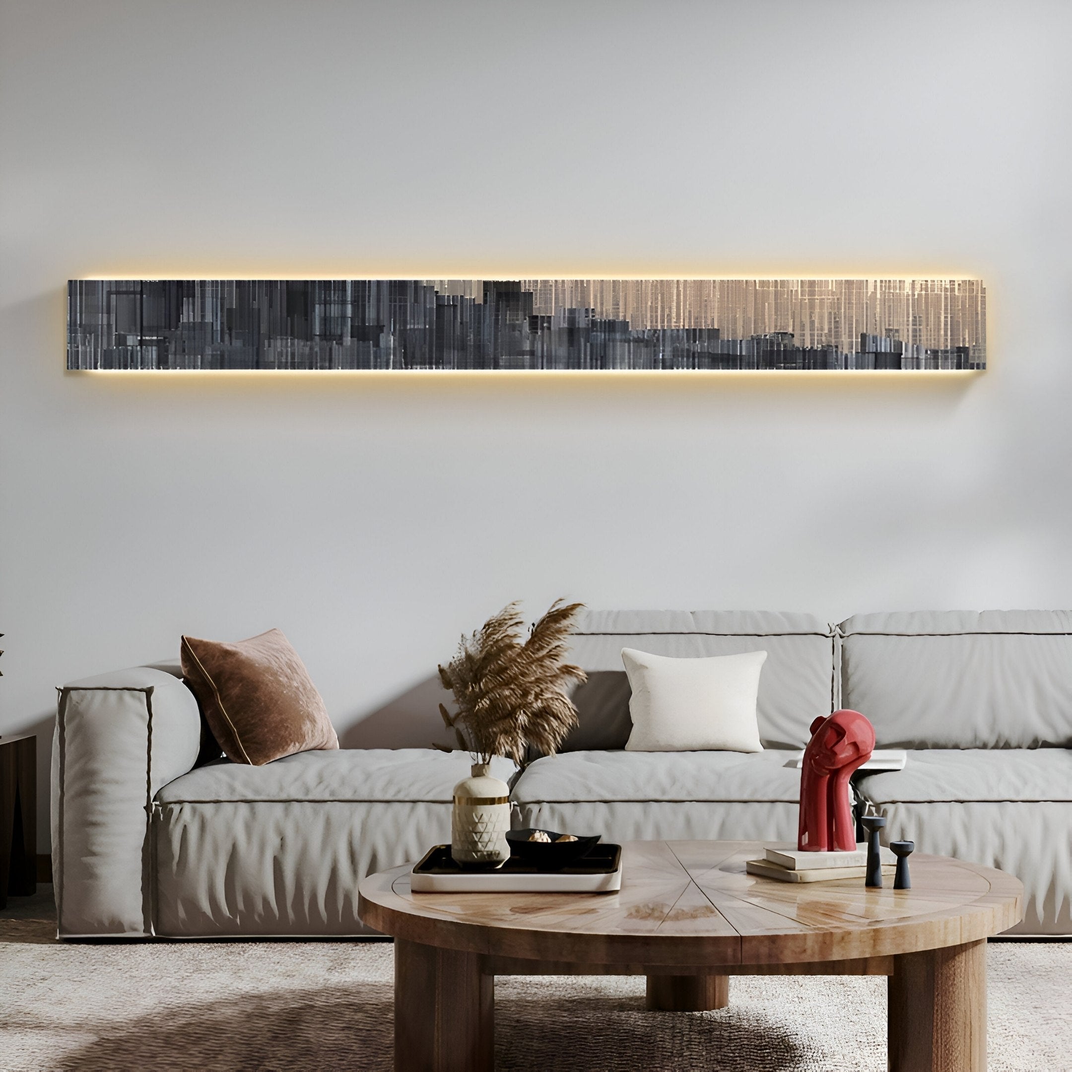 A modern living room showcases a gray couch with brown and beige pillows. A round wooden coffee table displays decor items. Above the couch, Giant Sculptures’ Radiance Charcoal Gold Canvas LED Wall Art adds intrigue, while neutral tones define this contemporary space.