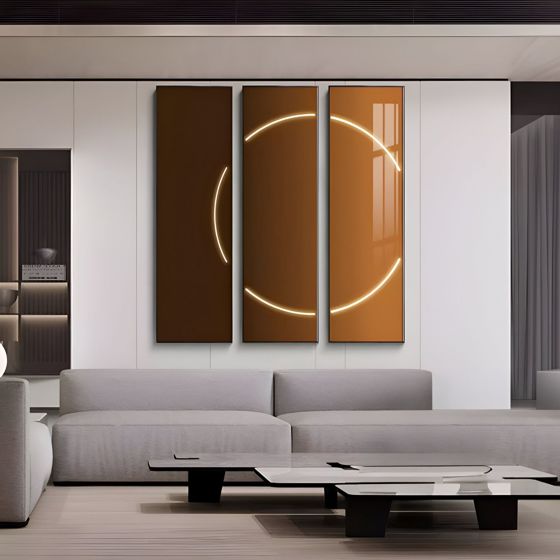 A modern living room features a gray sofa, a sleek coffee table, and the Helios Copper Crystal Porcelain LED Wall Art from Giant Sculptures, with glowing circles against a white wall. The minimalist design includes subtle shelving and warm lighting, complemented by an elegant metallic palette.