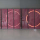 The Helios Ruby Crystal Porcelain LED Wall Art by Giant Sculptures features large vertical porcelain panels with translucent pink surfaces and circular neon lights, creating a warm glow. Faint reflections of furniture and framed artwork enhance the elegant setting.