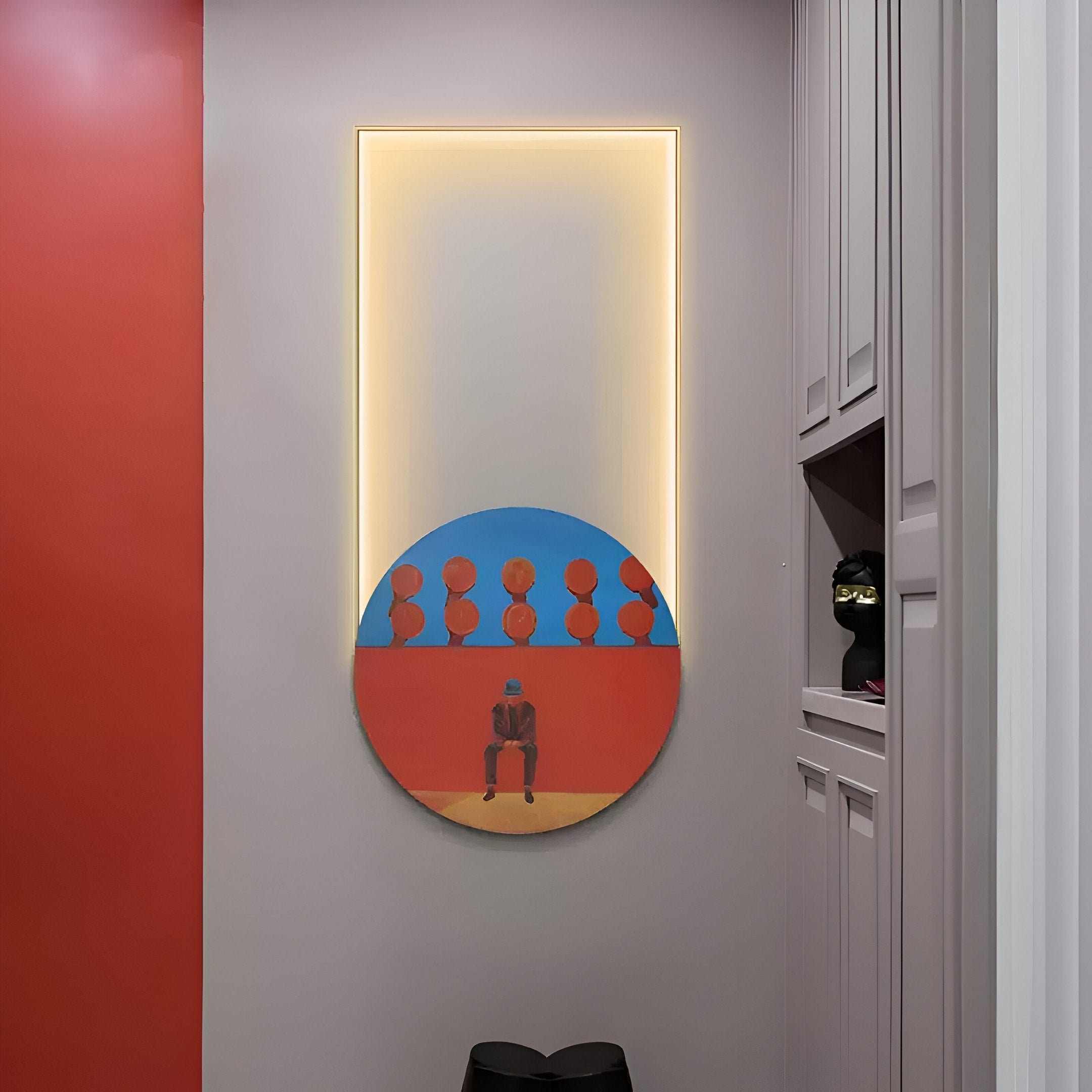 A round painting from Giant Sculptures Orion Crimson Silhouettes Oil Painting LED Wall Art collection is mounted on a wall with soft ambient lighting, depicting a person among circular shapes against red and blue. A shelf with a decorative object sits beside it.