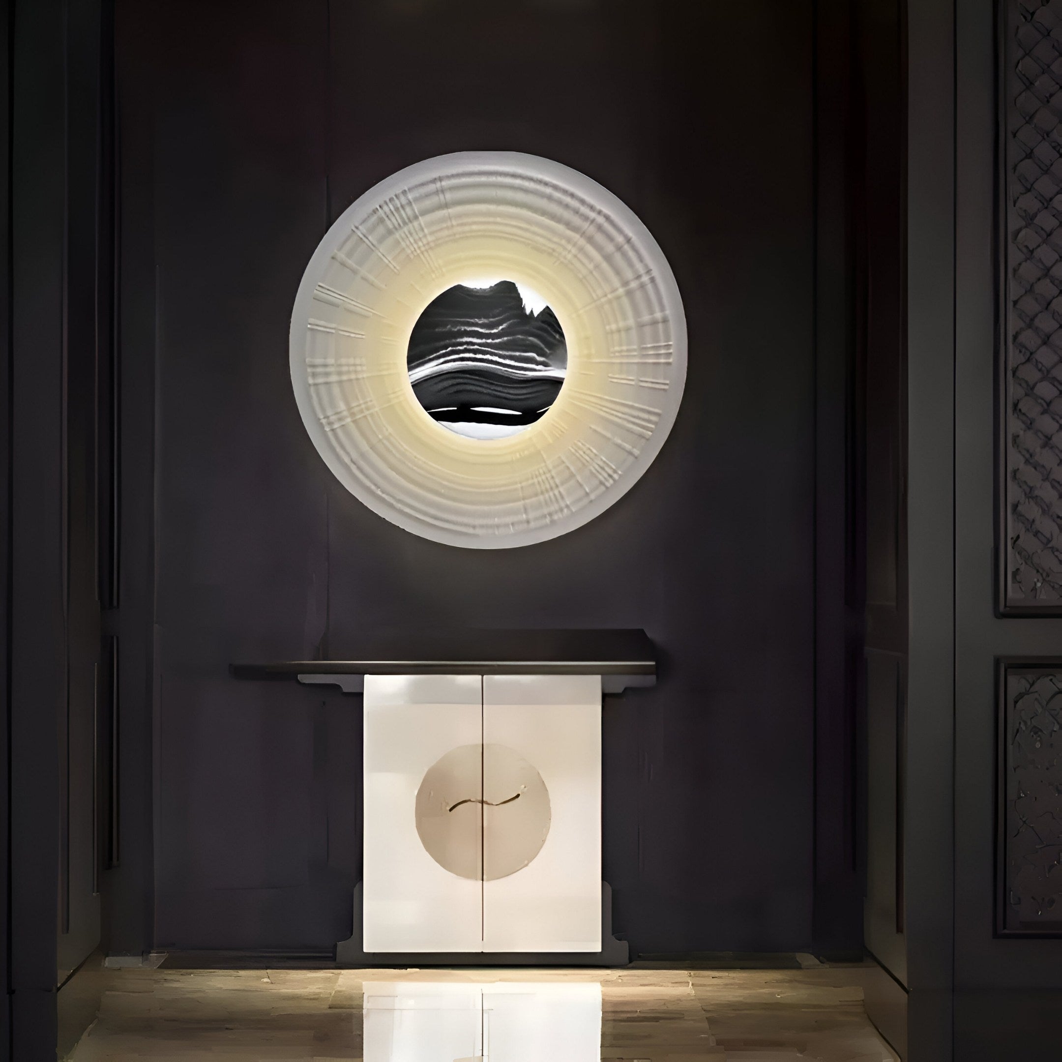 A modern interior highlights Giant Sculptures Ventus Onyx Strata Wood Carving 3D LED Wall Art—a circular wall mirror with abstract patterns and a glowing frame. A cabinet with wood carving accents complements the sleek, contemporary design against a dark wall, adding depth and elegance.