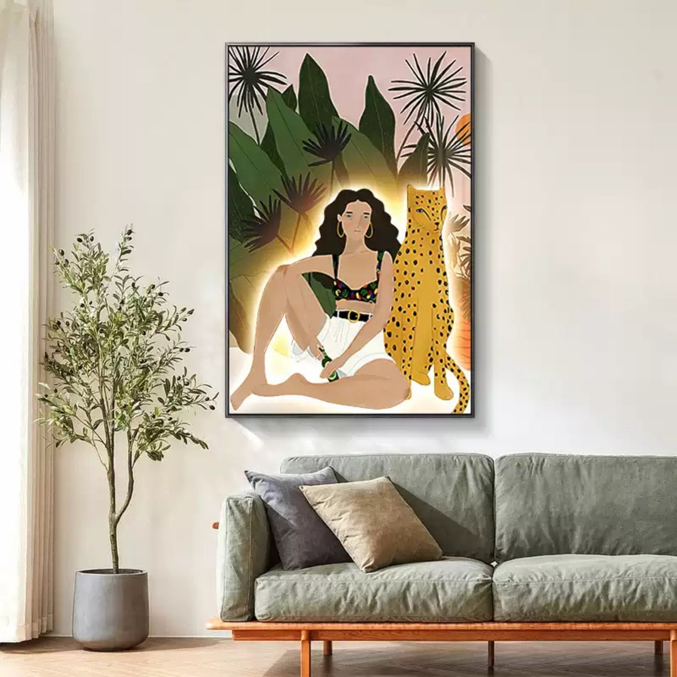 The Solana Wild Serenity Wood Relief 3D LED Wall Art by Giant Sculptures adorns the white wall above a gray couch, featuring a woman sitting with a leopard amidst lush tropical foliage against a soft pink backdrop. A nearby potted plant complements the vibrant ambiance.