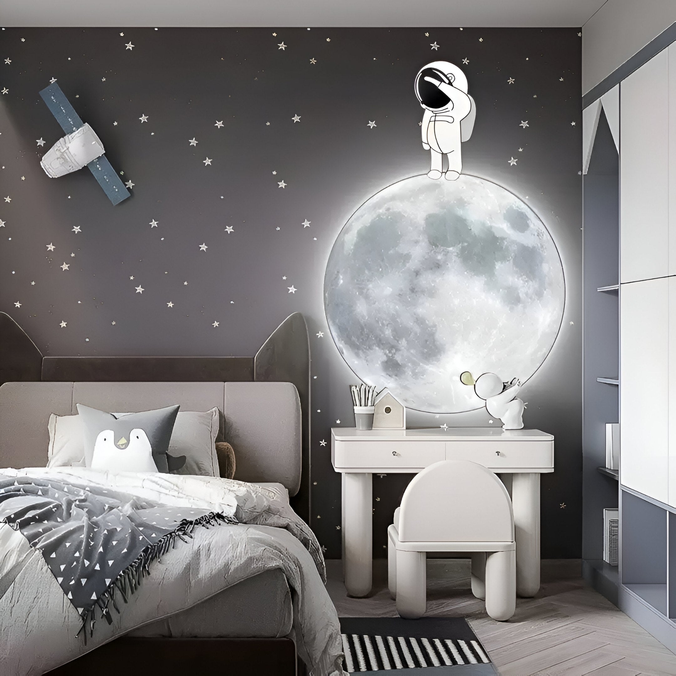 Bring a kids bedroom to life with cosmos decor featuring the Cosmos Astronaut Wonder UV Wood Carving LED Wall Art by Giant Sculptures. A mural of an astronaut on a glowing moon surrounded by stars and rockets pairs perfectly with star-patterned bedding and a small desk and chair.