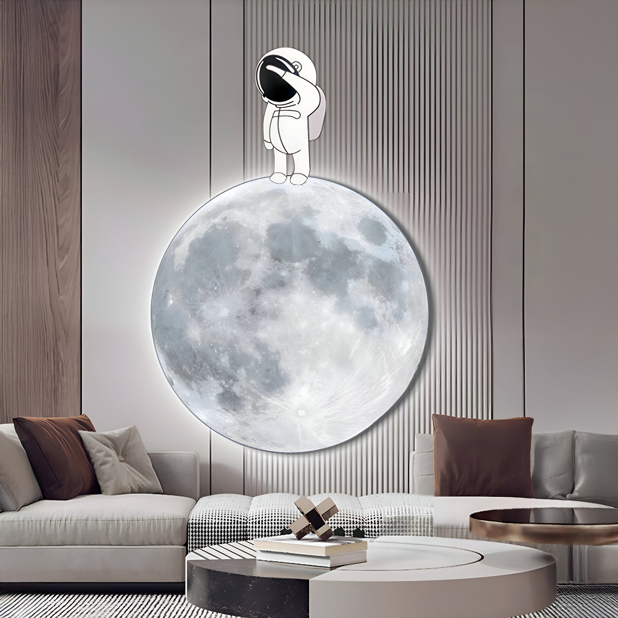 A modern living room showcases a large illuminated moon with the Cosmos Astronaut Wonder UV Wood Carving LED Wall Art by Giant Sculptures. A cartoon astronaut figure stands atop, accompanied by a circular coffee table and a grey sofa with assorted cushions.