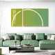 A modern living room features green sectional sofas with assorted pillows centered around a gray coffee table adorned with decor. Two large Enigma Lime Jade LED Wall Art pieces by Giant Sculptures in lime jade and yellow hang on the white wall, adding a contemporary touch.