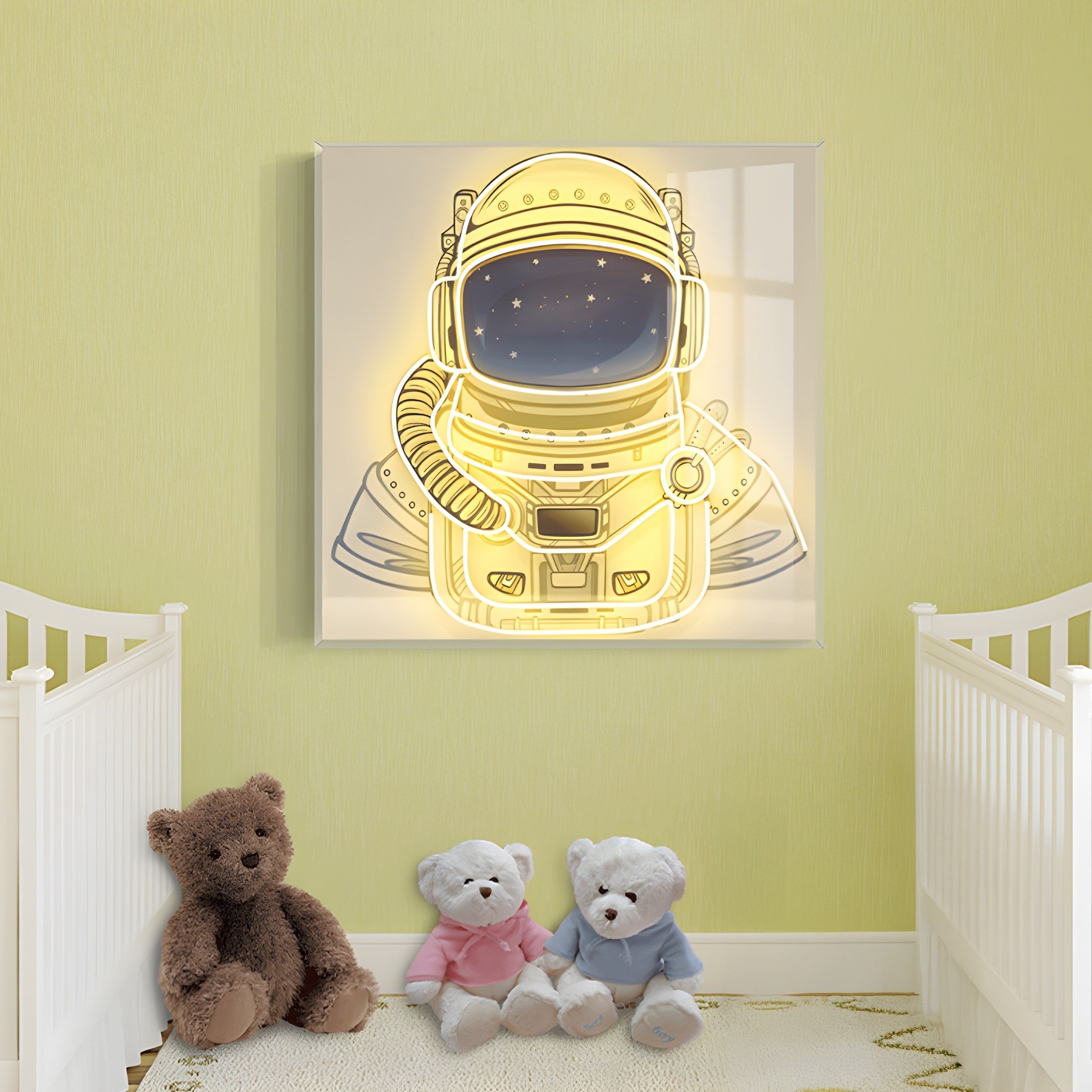 A nursery with light green walls has two white cribs on either side and three plush teddy bears between them. Centered above is the Stellar Auric Gold Acrylic 3D LED Wall Art by Giant Sculptures, boasting an astronaut theme that adds a cozy ambiance to the room.