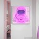 A room featuring Giant Sculptures Stellar Neon Orchid Acrylic 3D LED Wall Art, showcasing an astronaut helmet. Next to it, a sleek white desk and pink chair bathe the space in soft pastel pink and white tones that harmonize with the 3D LED accents.