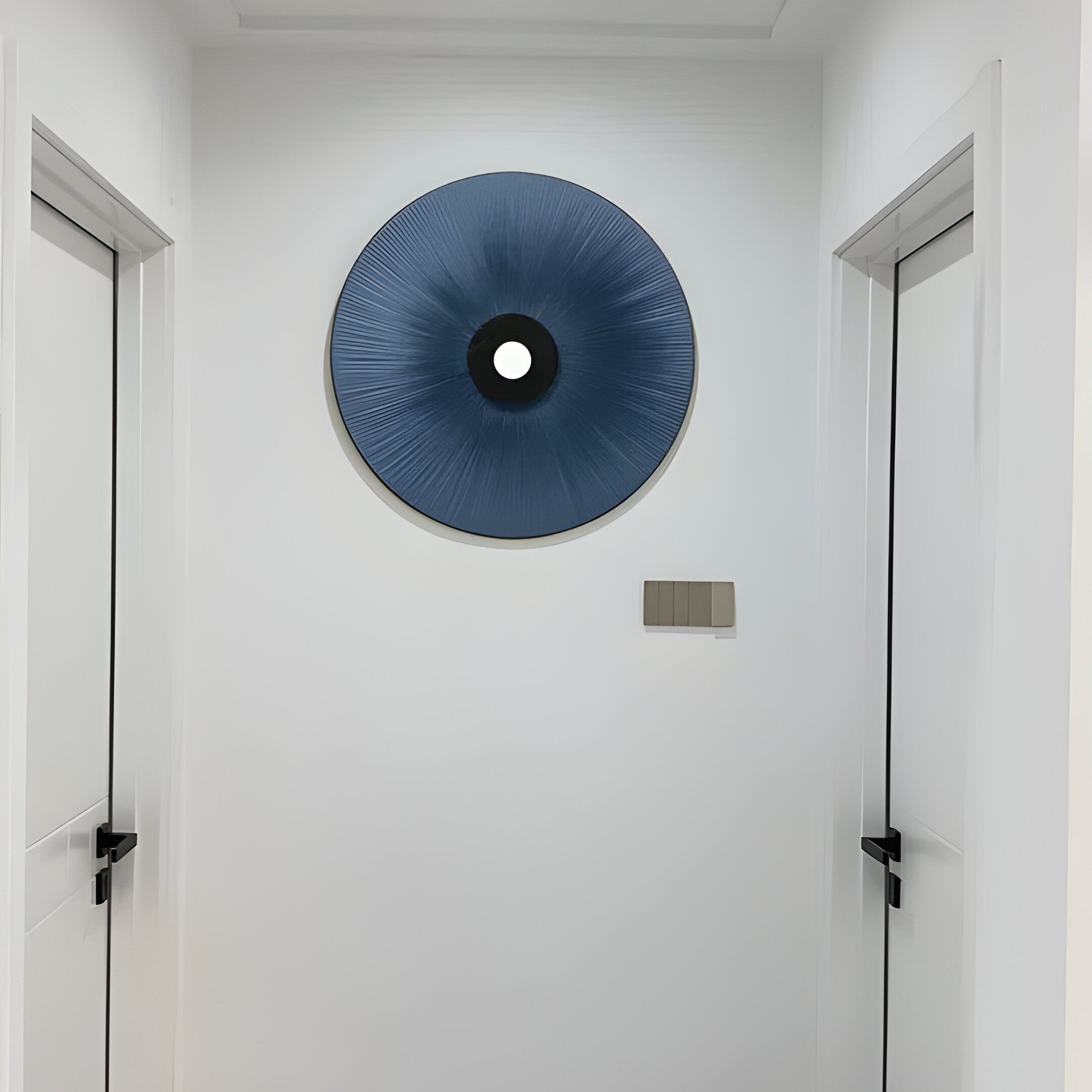 A minimalist hallway with white walls and doors features a blue circular wall art piece with an indigo hue. The black center adds modern elegance, echoing the aesthetic of Giant Sculptures Vanguard Midnight Indigo Leather 3D LED Wall Art.