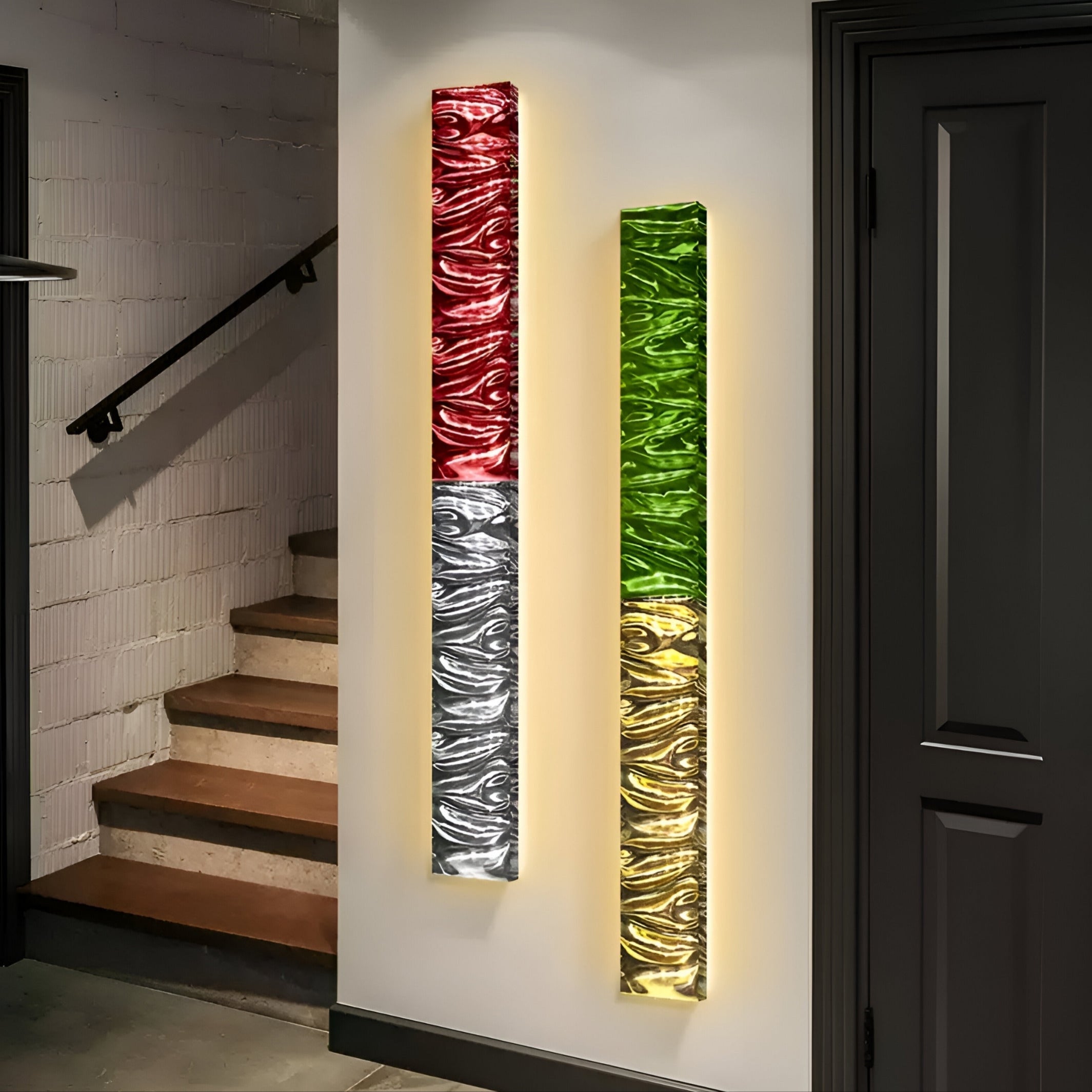 Two Textura 3D Red and Silver Leather Design Wall Art pieces by Giant Sculptures showcase modern design principles. The left panels red and silver masterpiece balances the right’s green and gold hues, displayed on a white wall near a staircase with dark doors.