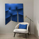 A modern interior features a white armchair with a blue cushion made of elastic fabric. Beside it, a sleek floor lamp complements the Giant Sculptures Contours Dynamic Blue 3D Wooden Wall Art, enhancing the contemporary style against a neutral-colored wall.