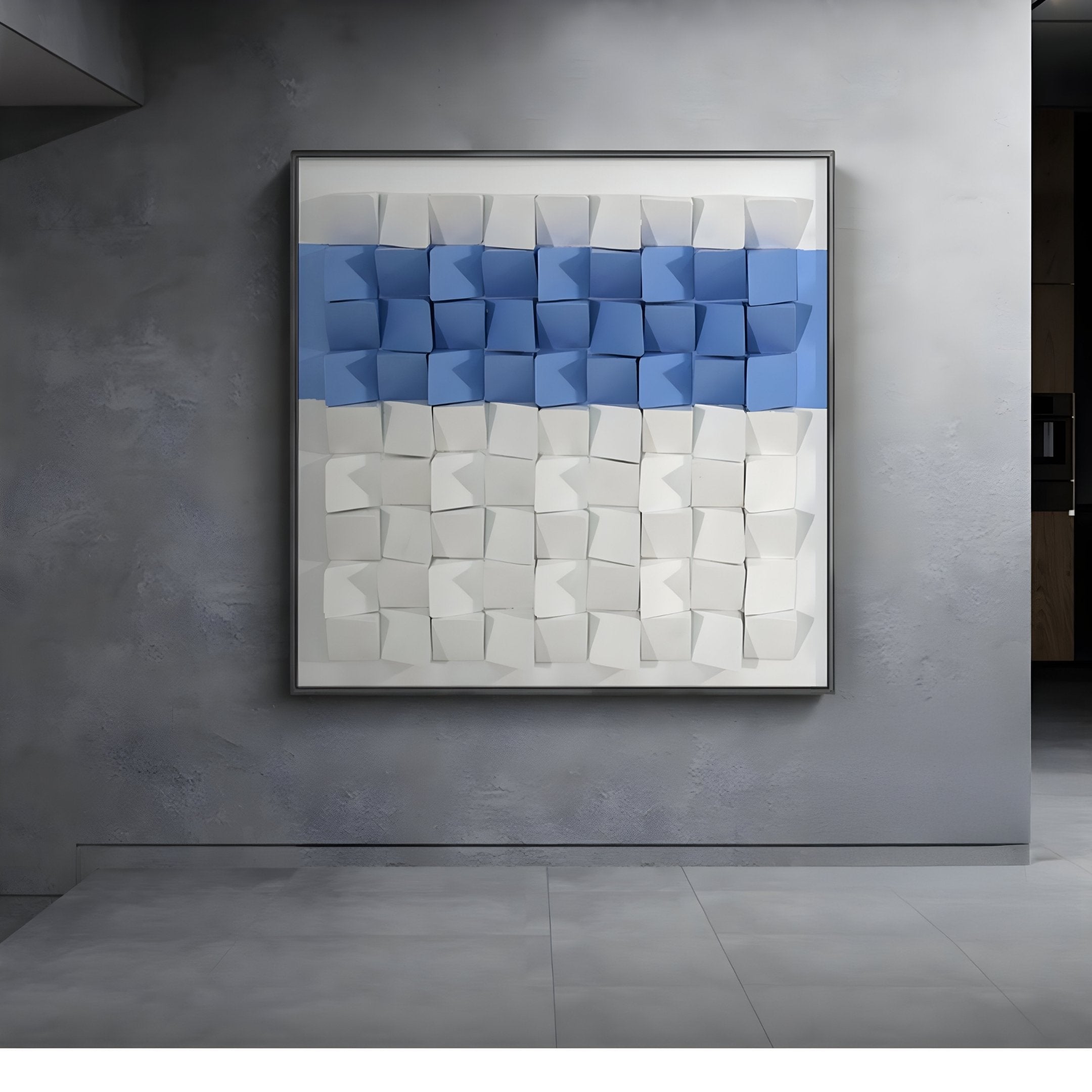 The Tessera White & Blue I Geometric Wood 3D Wall Art by Giant Sculptures, featuring a hand-painted geometric design of three-dimensional blue and white cubes, adds depth and texture to the minimalist gray wall.