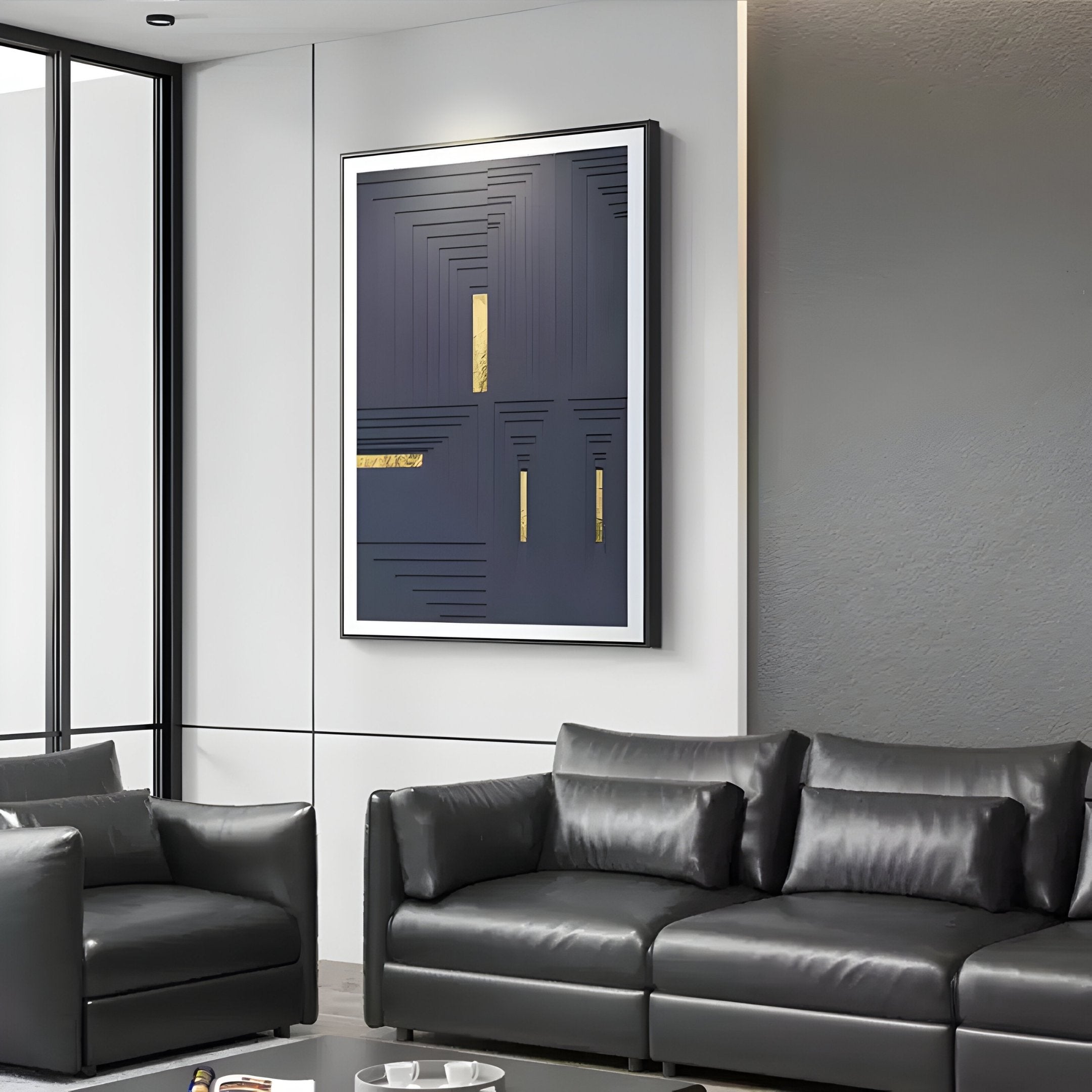 A modern living room features a dark leather couch and armchair with midnight blue accents. A black and gold geometric abstract painting adorns the wall, alongside Giant Sculptures Striato Midnight Blue 3D Wooden Wall Art With Gold Accent. Large windows flood the space with natural light.