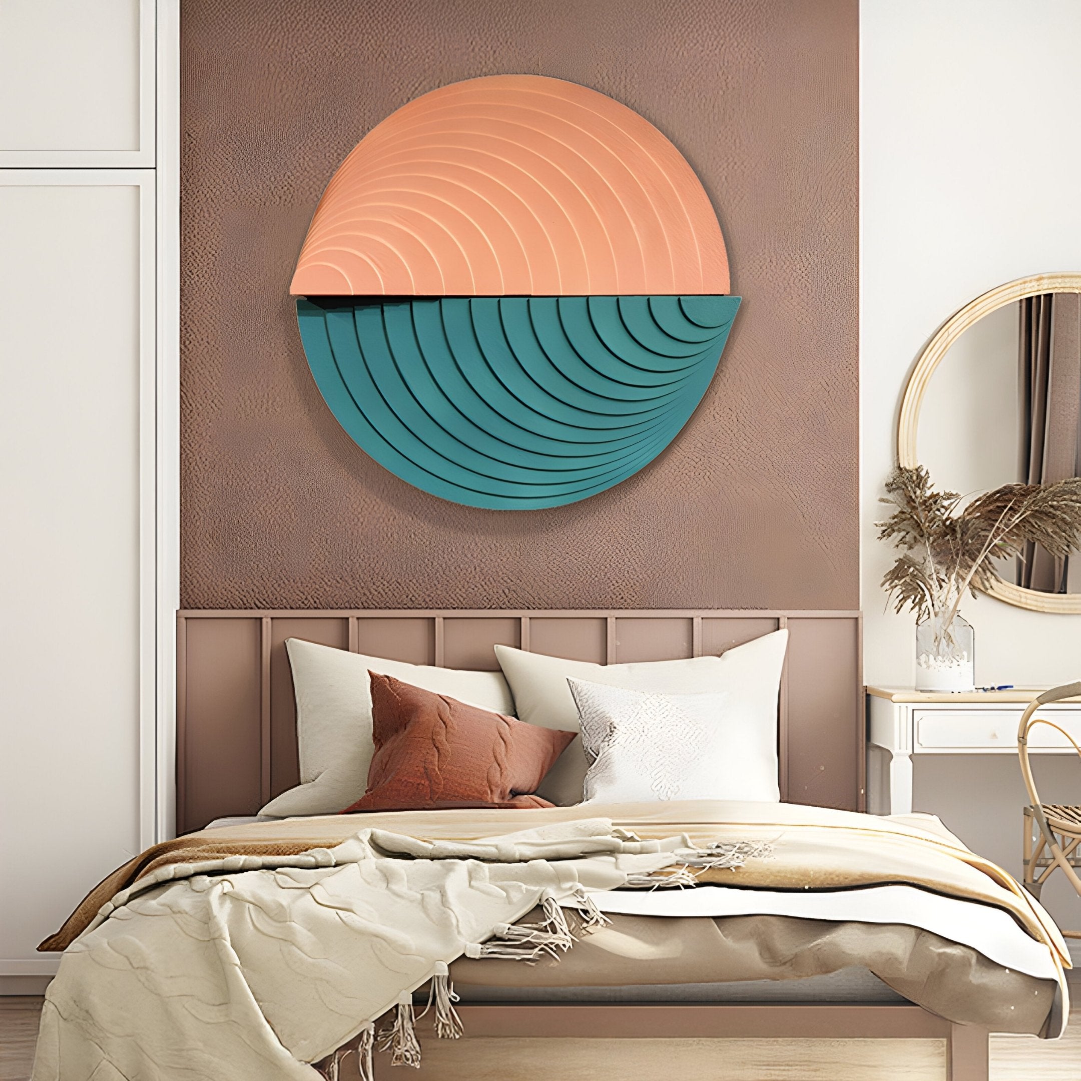 The cozy bedroom showcases a bed with beige and rust pillows, a cream blanket, and an exquisite Orbitals Peach & Teal wood-carved 3D wall art by Giant Sculptures. A round mirror and dried flowers embellish the small table beside the bed.