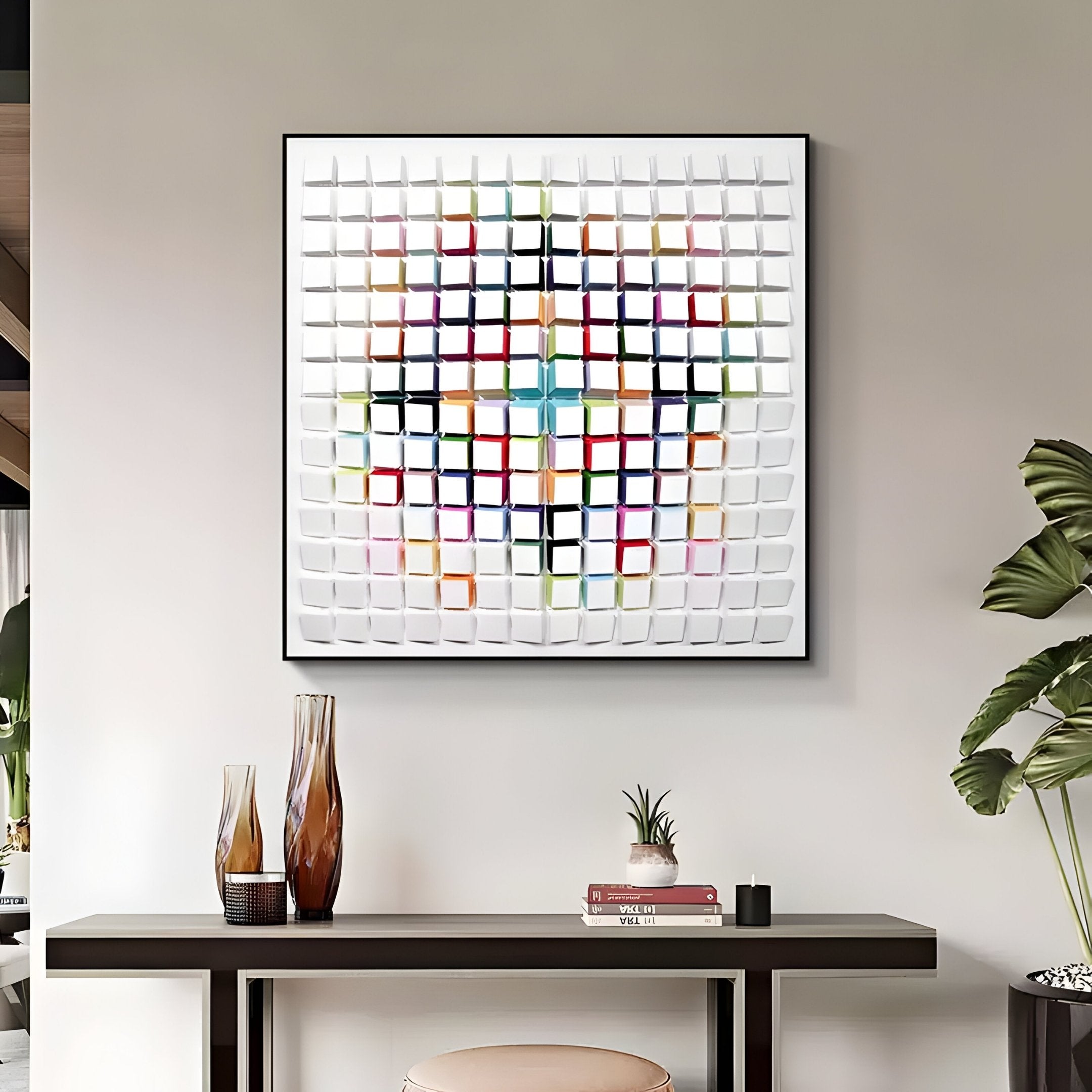 A modern interior features the Giant Sculptures Prismatrix Multicolor Geometric Wood Collage 3D Wall Art with vibrant squares. Below is a sleek table with decorative vases, a small plant, and books, while a tall plant to the right brings a natural touch.