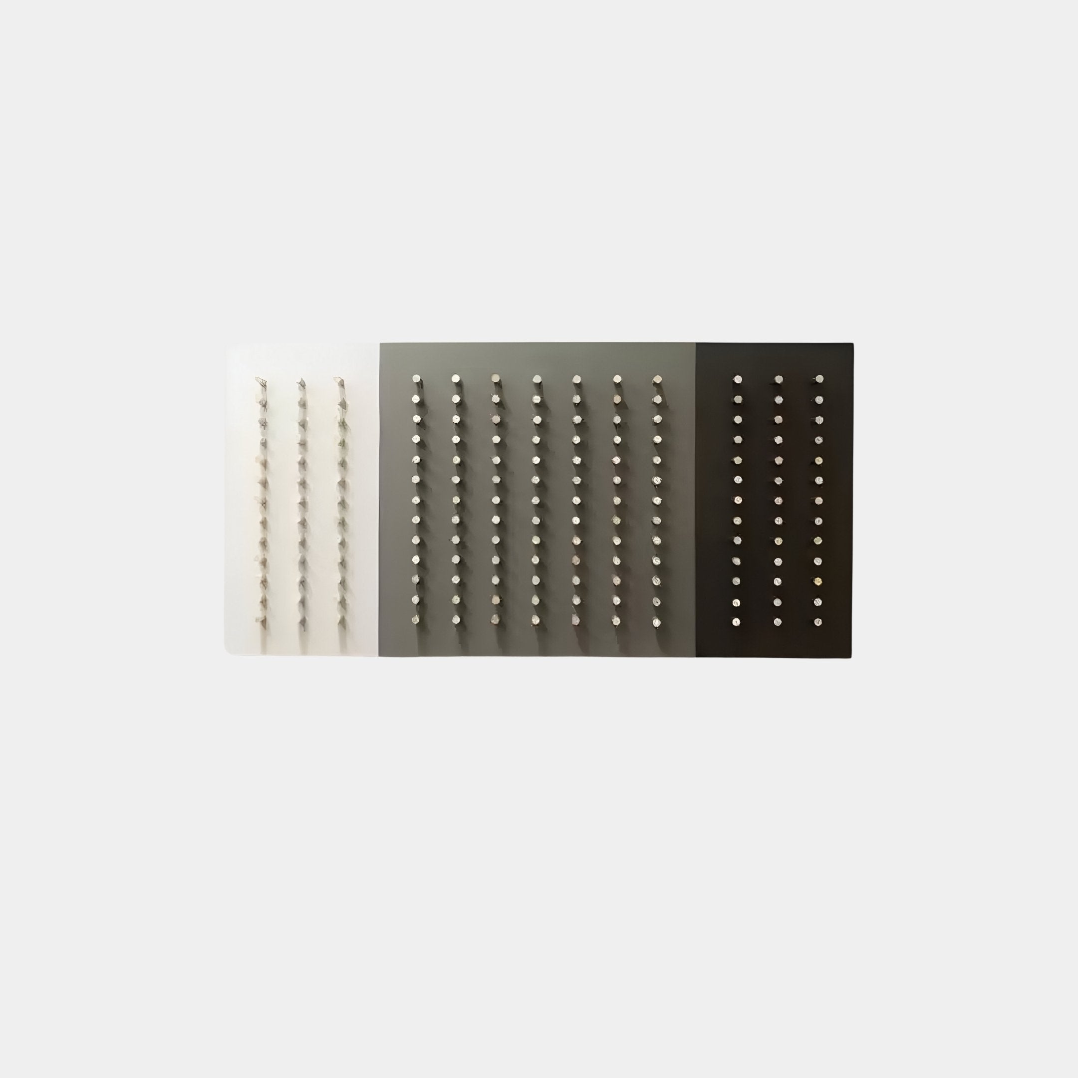 The Contrasto Monochrome Symmetry 3D Wooden Wall Art by Giant Sculptures enhances minimalist interiors with its three-panel design in light gray, gray, and dark gray. Each panel is vertically adorned with evenly spaced metallic studs for a visually harmonious effect.