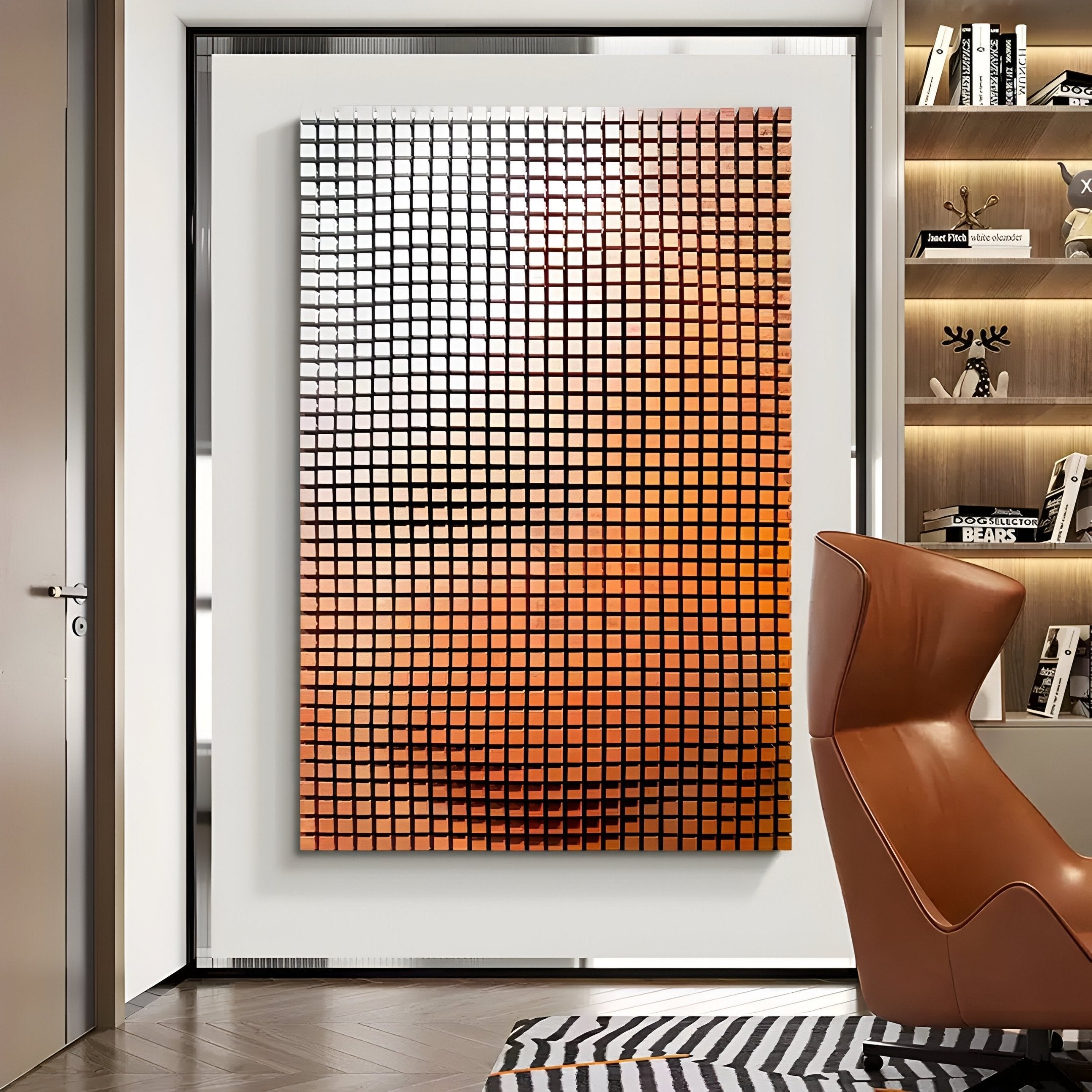 A modern room features the Reflexion Sunset Orange Cube Mosaic 3D Wooden Wall Art by Giant Sculptures, with metallic squares in a sunset gradient. A sleek leather chair faces it, flanked by a decor-filled bookshelf on the right. A striped carpet adds contrast to the space.