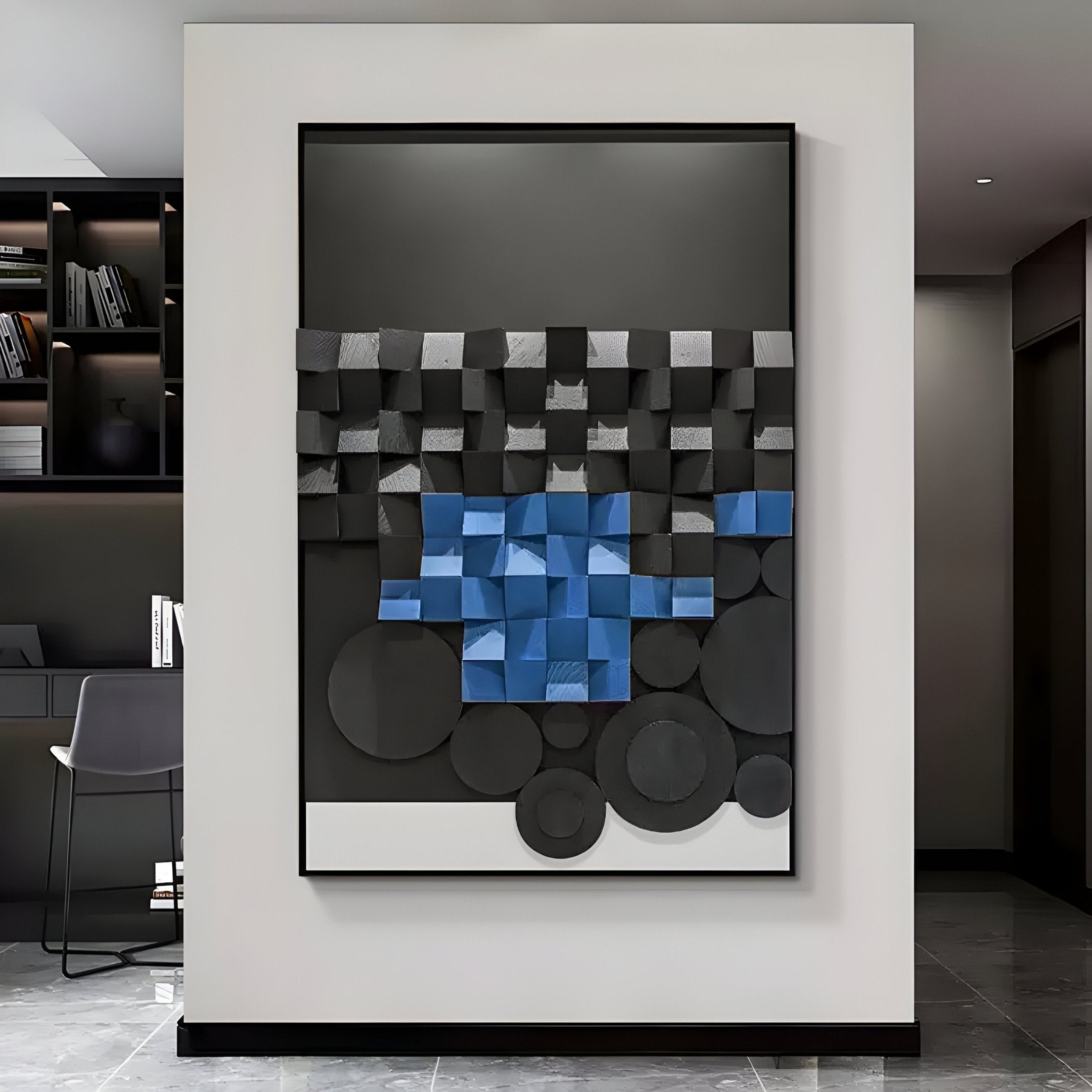 The Obscura Black & Blue Geometric 3D Wooden Wall Art by Giant Sculptures displays a grid of black and blue cubes above overlapping dark circles in a modern, minimalistic room featuring a white wall, bookshelf, and chair.