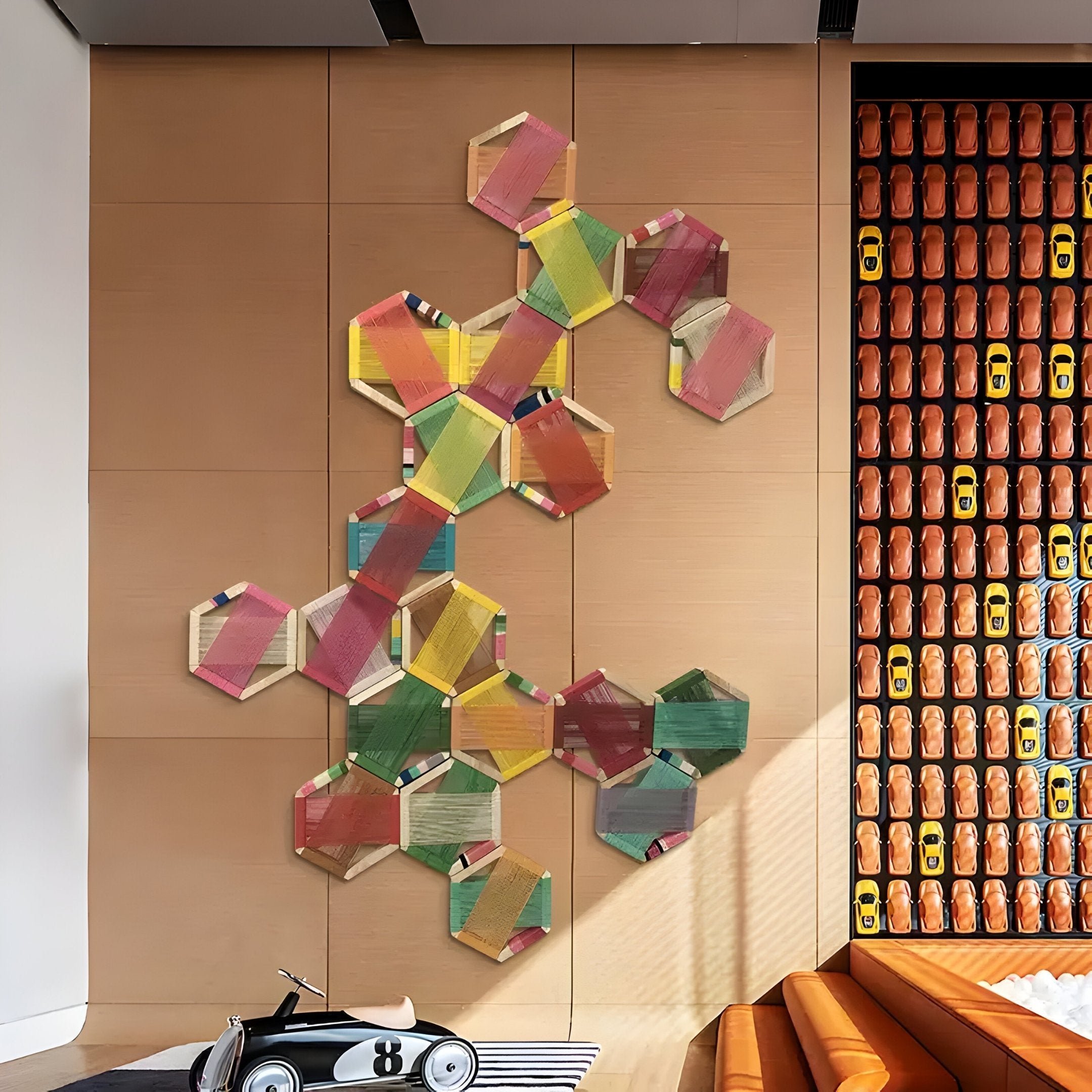 A wooden wall highlights the Giant Sculptures Spectra V Multicoloured Interwoven Hexagonal Frame 3D Wall Art. Nearby, a toy car shelf and a childrens ride-on car enrich the modern interiors, infusing charm into this playful space.