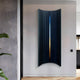 A modern interior features the Illumina Blue Vertical Gradient 3D Wall Art by Giant Sculptures, showcasing vertical hand-painted layered panels. The minimalist design includes wooden slats, a large potted plant in the foreground, and light wood flooring.