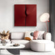 A modern living room showcases a white curved sofa with abstract pillows. Mounted on the wall is the Delinea Crimson Red Stretch Fabric 3D Wood Relief Wall Art by Giant Sculptures, adding depth. A round lamp and a small table with decorative items enhance the stylish ambiance.