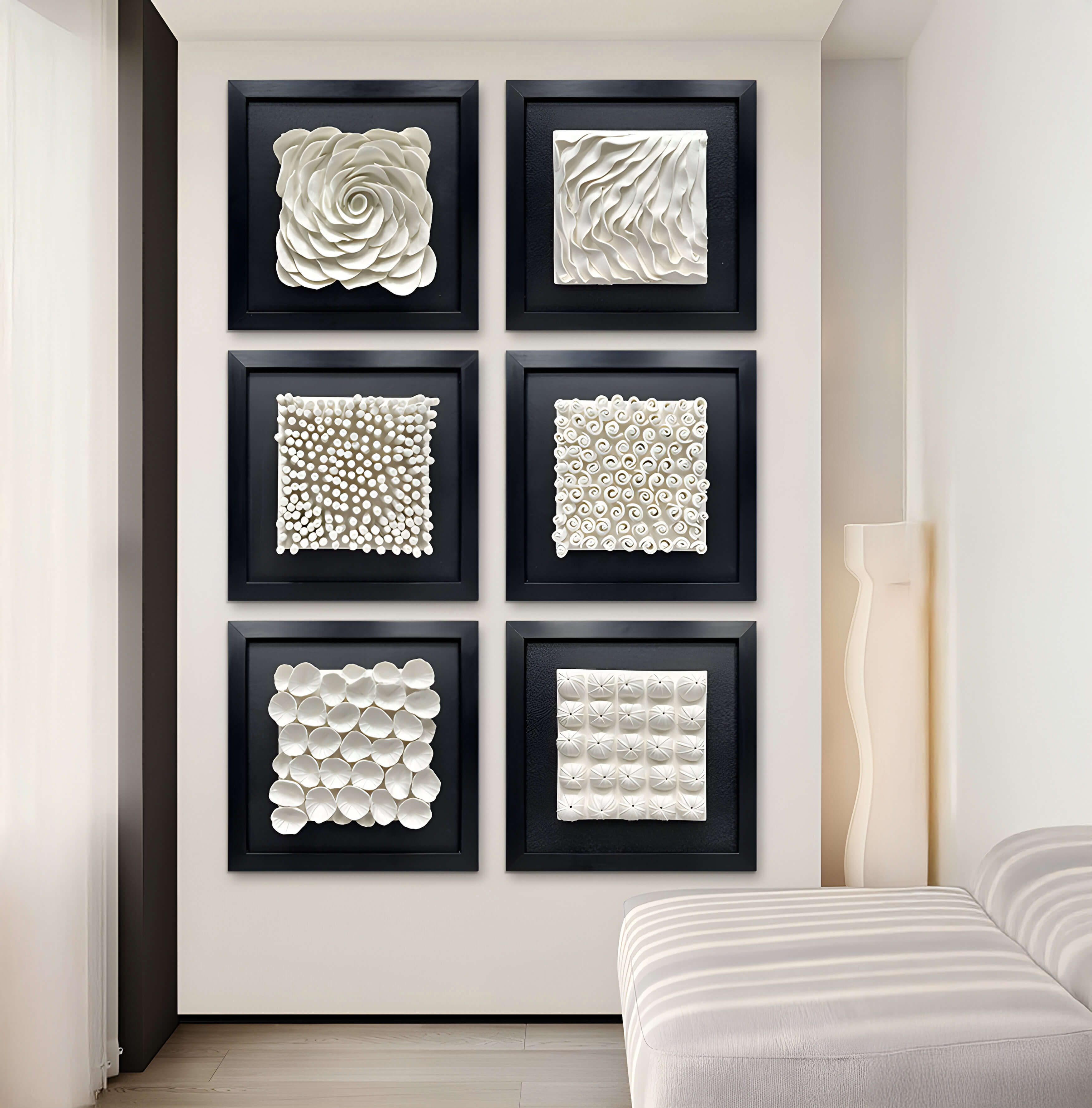 A curated set of six black-framed ceramic artworks decorates this stylish interior. The pieces feature sculptural white textures, including soft floral swirls, rhythmic waves, spirals, and grid-like impressions, blending nature-inspired and geometric elements.