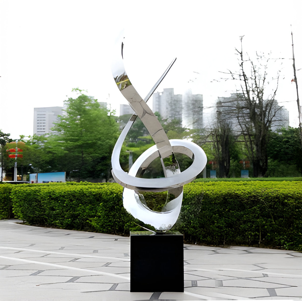 The sculpture in front of a modern building with water reflections below.